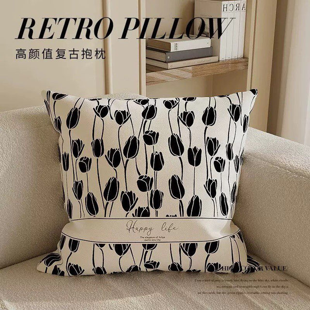Decorative pillow with black tulip pattern on a beige sofa
