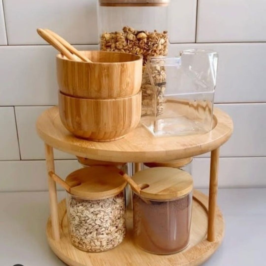 A bamboo rotating spice rack with multiple compartments, some of which are filled with spice jars. The rack is placed on a kitchen counter.
