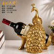 Gold resin peacock wine bottle holder displaying a standard wine bottle on a tabletop.